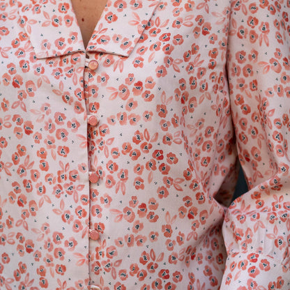 Detail of a handmade blouse sewn in Feline Floral viscose fabric, featuring a notched collar and button front. The coral floral print on a pink background highlights the fabric’s soft drape and flow.