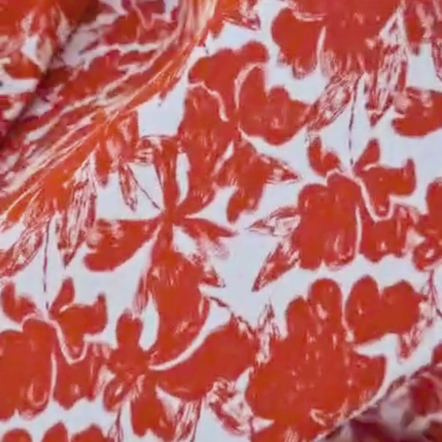 Video of viscose crepe, with an orange floral design and white background